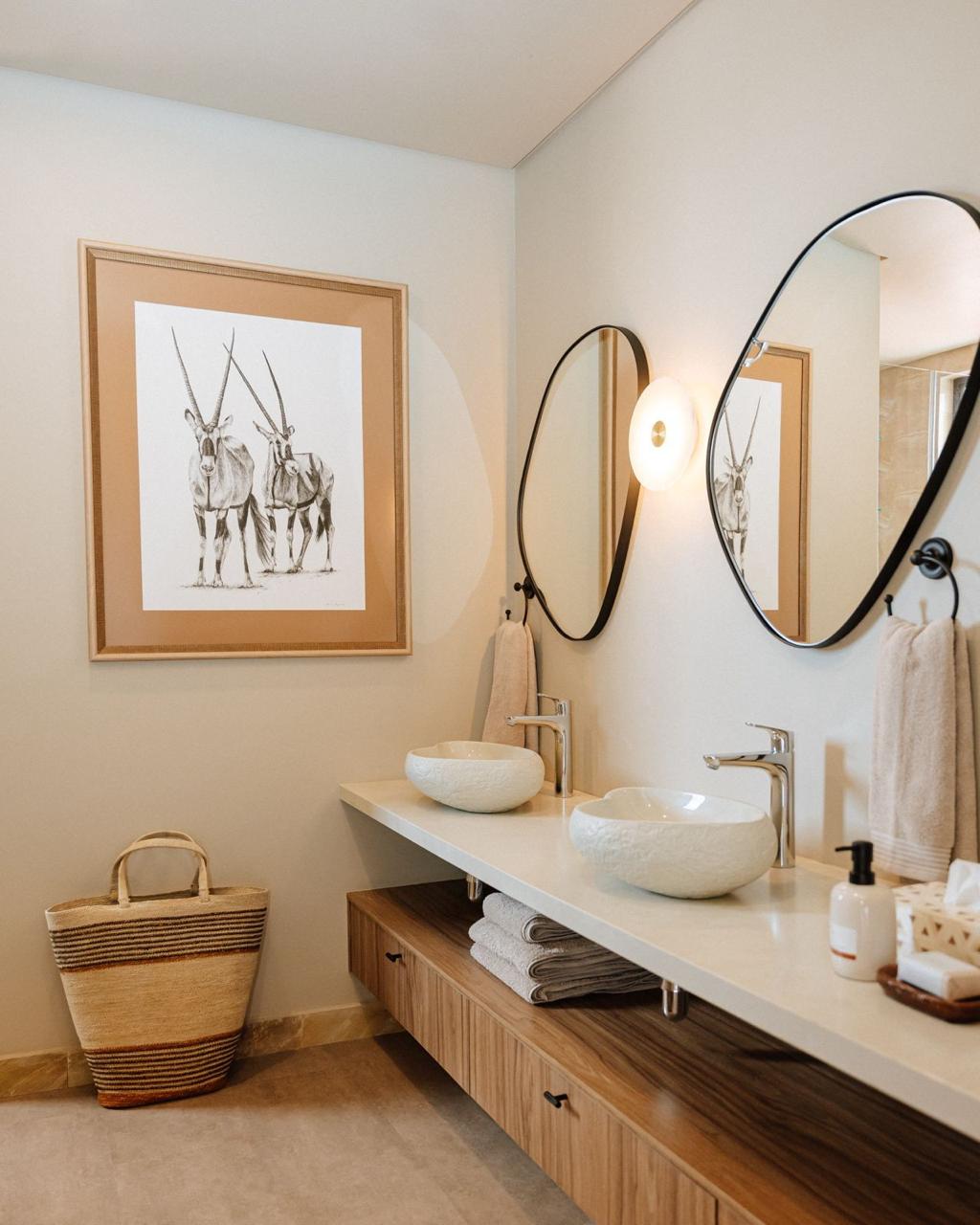 Warm timber double vanity with sculptural mirrors and countertop basins