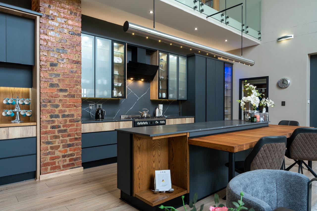 Modern kitchen and dining island with dark cabinetry and a brick feature column