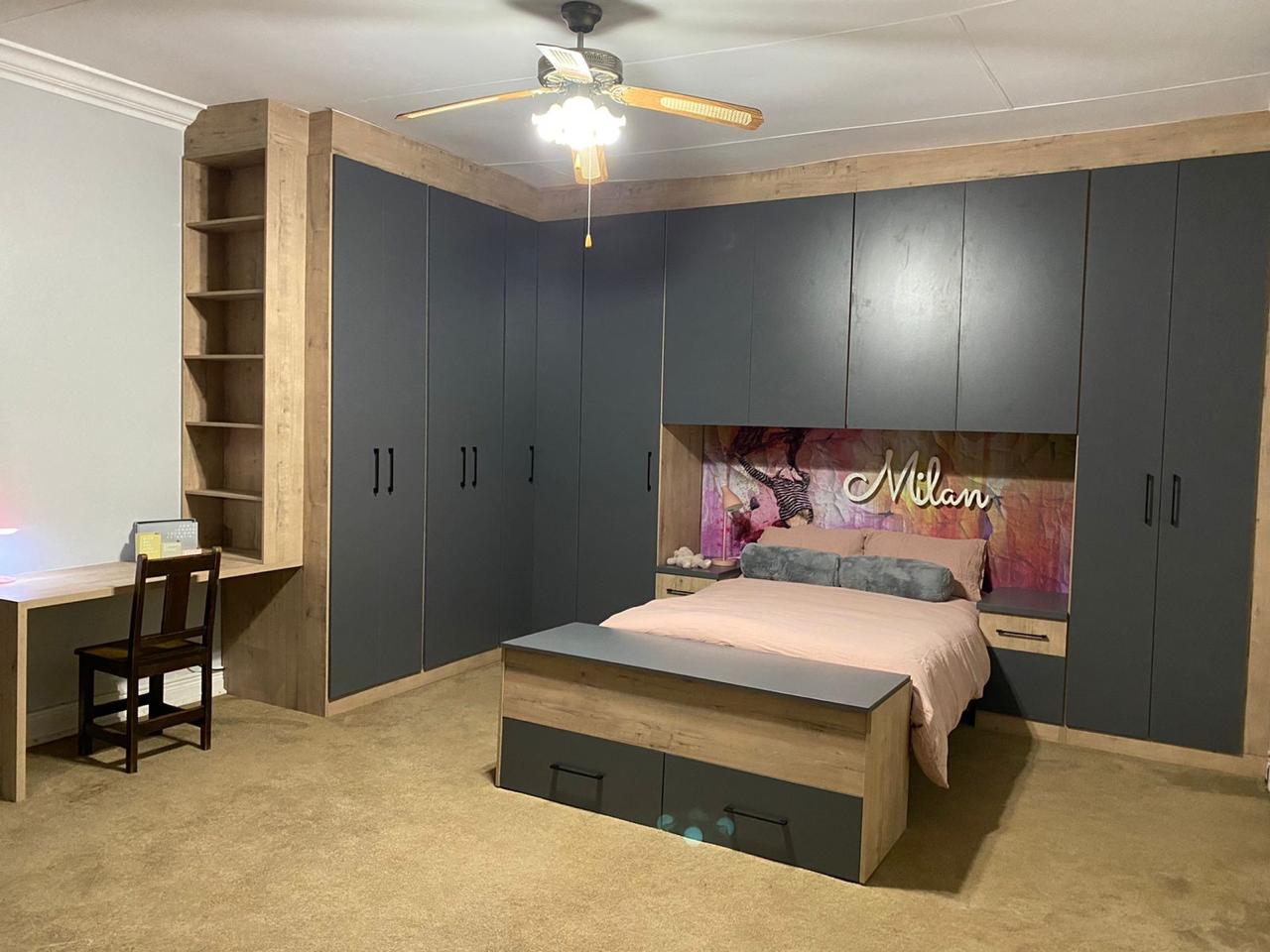Bedroom with full-height charcoal wardrobes and integrated study desk