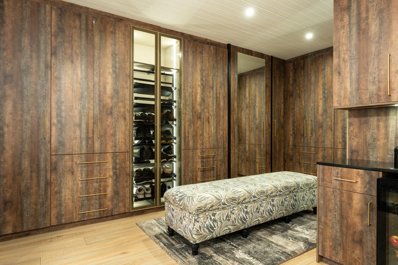 Walk-in wardrobe with illuminated shoe storage and warm timber cabinetry