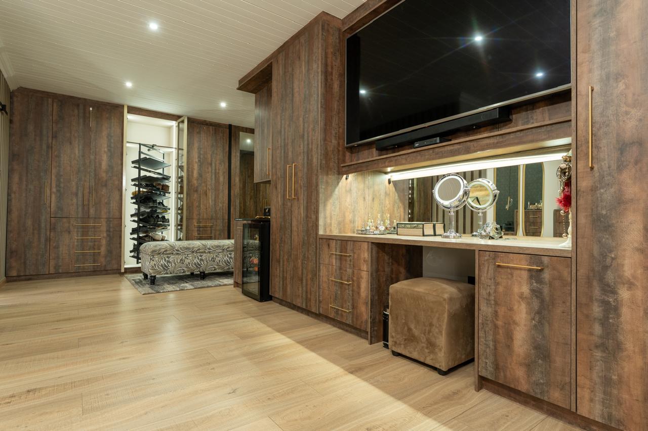 Spacious dressing room with integrated television and vanity cabinetry