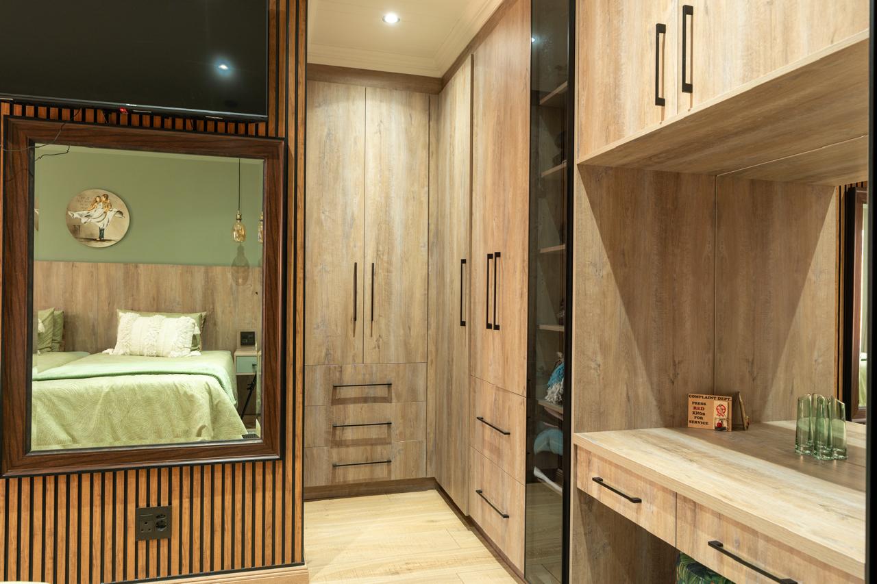 Bedroom dressing area with timber wardrobes and slatted mirror wall