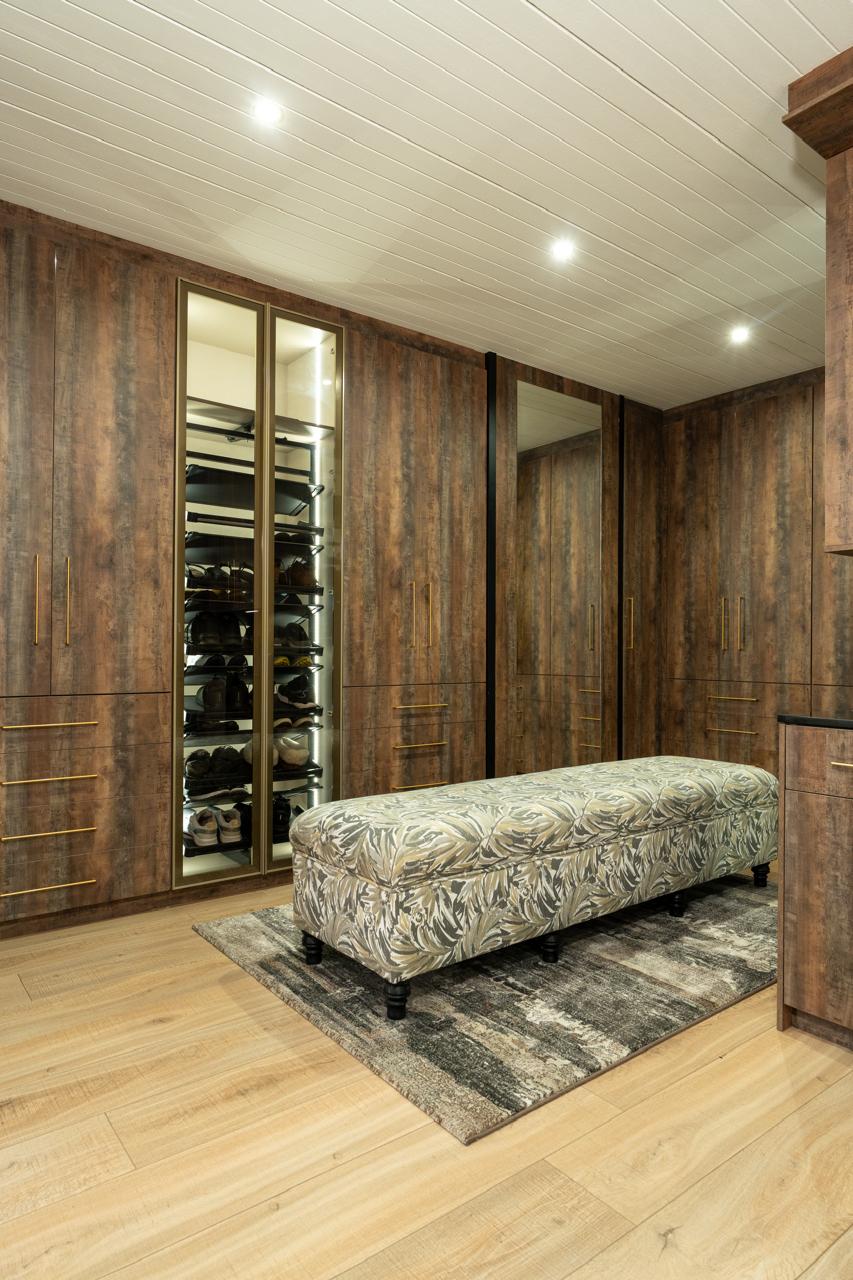Walk-in wardrobe with illuminated shoe storage and upholstered bench